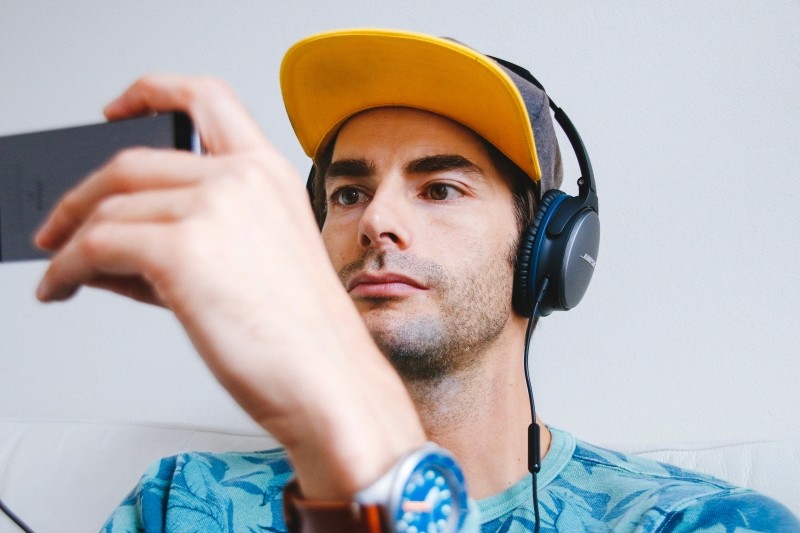 man with headphones looking at phone